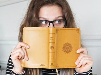 Woman with Bible in front of face.