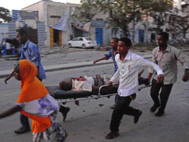 People carry a victim of a terror attack at the Ambassador Hotel, after Somalia's Al-Qaeda-linked Shabaab on June 1, 2016, launched a deadly attack on a top Mogadishu hotel popular with MPs, setting off a car bomb and fighting security forces inside the complex. Somalia's Al-Qaeda-linked al-Shabaab group was chased …