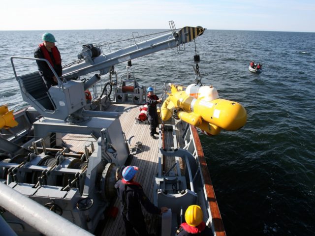 Navy members pull up a submersible device during the Operation Open Spirit, the latest in