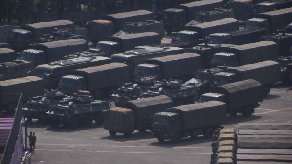 In this image made from video, armed police vehicles are parked outside Shenzhen Bay Stadium in Shenzhen, near Hong Kong, Friday, Aug. 16, 2019. Satellite photos show what appear to be armored personnel carriers and other vehicles belonging to the China's paramilitary People's Armed Police parked in a sports complex in the city of Shenzhen, in what some have interpreted as a threat from Beijing to use increased force against pro-democracy protesters across the border in Hong Kong.(AP Photo/Dake Kang)