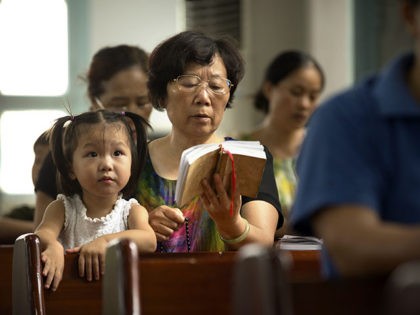 In this July 30, 2015 photo, parishioners of Lower Dafei Catholic Church hold an impromptu prayer vigil as they wait for Chinese police, security guards, and government workers to arrive and cut down their church's cross in Lower Dafei Village in Yongjia County in eastern China's Zhejiang Province. A massive …