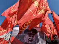 TOPSHOT - A Russian Communist party activist holds a red flag as he stands next to a banner with a portrait of late Soviet leader Joseph Stalin during a May Day rally in central Moscow on May 1, 2016. / AFP / KIRILL KUDRYAVTSEV (Photo credit should read KIRILL KUDRYAVTSEV/AFP/Getty …