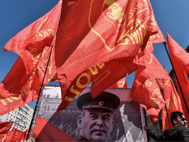 TOPSHOT - A Russian Communist party activist holds a red flag as he stands next to a banner with a portrait of late Soviet leader Joseph Stalin during a May Day rally in central Moscow on May 1, 2016. / AFP / KIRILL KUDRYAVTSEV (Photo credit should read KIRILL KUDRYAVTSEV/AFP/Getty …