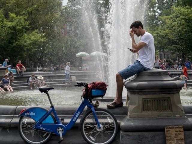 NEW YORK, NY - JULY 17: People cool off near the fountain at Washington Square Park during