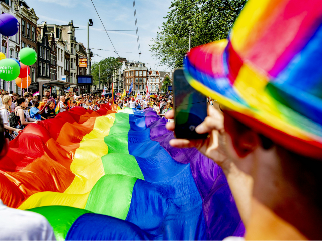 People take part in the Gay Pride Walk and hold a big LGBT flag during the opening of the Pride Amsterdam festival, in Amsterdam on July 27, 2019 (Photo by Robin UTRECHT / ANP / AFP) / Netherlands OUT (Photo credit should read ROBIN UTRECHT/AFP/Getty Images)