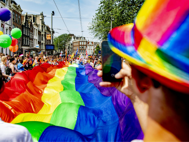 People take part in the Gay Pride Walk and hold a big LGBT flag during the opening of the