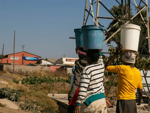 Women carry 20 litre containers of water in the streets of Mabvuku on August 1, 2019 in Harare, Zimbabwe. Zimbabwe is facing an acute water shortage after this year’s drought, compounded by poor water management. Rainfall is down 25 percent from the annual average, according to the Zimbabwean government, leaving …