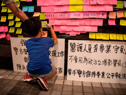 A boy writes on a Lennon Wall at a protest held by medics in the Central District of Hong