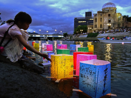 This August 6, 2019 picture shows a girl floating lanterns to mourn atomic bomb victims on the Motoyasu river beside the atomic bomb dome during the 74th anniversary of the atomic bombing in Hiroshima. - JAPAN OUT (Photo by JIJI PRESS / JIJI PRESS / AFP) / Japan OUT (Photo …