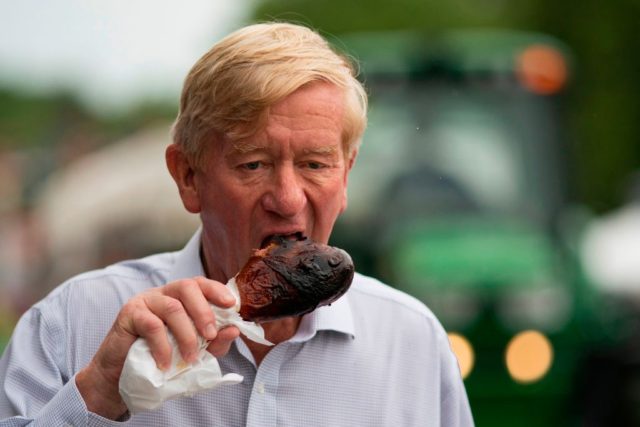 Republican presidential candidate Bill Weld eats a turkey leg as he walks through the Iowa