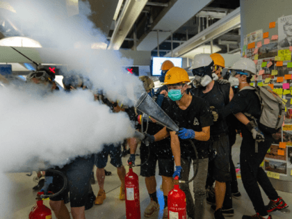 Protestors spray fire extinguishers during a protest at the Yuen Long MTR station on Augus