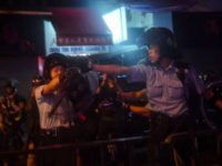 TOPSHOT - Police officers point their guns at protesters in Tseun Wan in Hong Kong on August 25, 2019 in the latest opposition protests to a planned extradition law that has since morphed into a wider call for democratic rights in the semi-autonomous city. - A Hong Kong police officer …