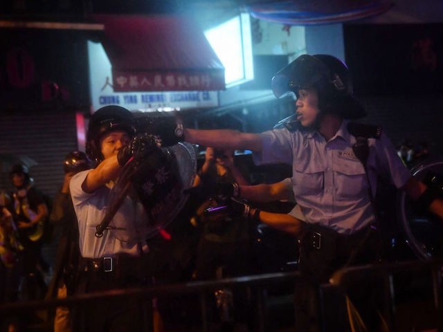 Police officers point their guns at protesters in Tseun Wan in Hong Kong on August 25, 201