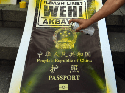 Philippine legislator Walden Bello (R-arm in frame) sprays paint on a placard featuring a mock cover of a Chinese passport during a demonstration in front of the Chinese consular office in Manila on November 29, 2012 against reports that Chinese passports contain a map showing most of the China South …