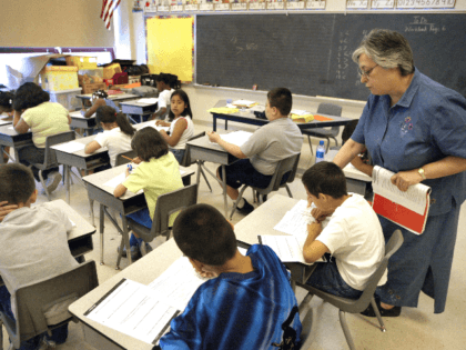 Teacher Arlene Lebowitz assists a student in her third-grade class during summer school July 2, 2003 in Chicago, Illinois. A record number of students are expected at summer school due to a strong showing for a new voluntary program for mid-tier students and strict application of non-ITBS (Iowa Tests of …