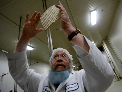 Rabbi Yaakov Horowitz examines the holes in a sheet of baked matzo from the matzo producti