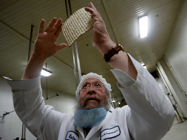 Rabbi Yaakov Horowitz examines the holes in a sheet of baked matzo from the matzo producti