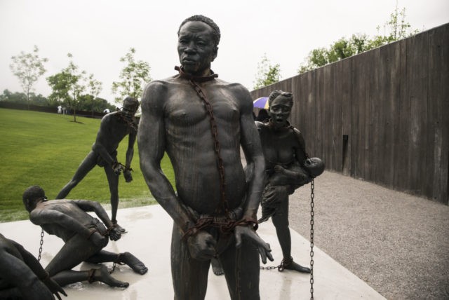 MONTGOMERY, AL - APRIL 26: A sculpture commemorating the slave trade greets visitors at the entrance National Memorial For Peace And Justice on April 26, 2018 in Montgomery, Alabama. The memorial is dedicated to the legacy of enslaved black people and those terrorized by lynching and Jim Crow segregation in …