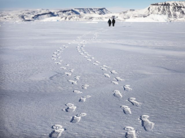 PITUFFIK, GREENLAND - MARCH 26: Project scientist Nathan Kurtz and senior support scientist Jeremy Harbeck walk on their way to survey an iceberg locked in sea ice near Thule Air Base on March 26, 2017 in Pituffik, Greenland. NASA's Operation IceBridge is flying research missions out of Thule Air Base â¦