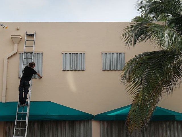 MIAMI BEACH, FLORIDA - AUGUST 30: Endre Eles places a hurricane shutter over a window as h