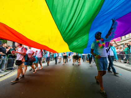LONDON, ENGLAND - JUNE 25: Marchers walk with a giant rainbow flag as the LGBT community c