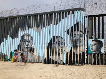 Children play in front of a new mural on the Mexican side of a border wall in Tijuana, Mexico Friday, Aug. 9, 2019. The mural shows faces of people deported from the U.S. with barcodes that activate first-person narratives on visitors' phones. Lizbeth De La Cruz Santana conceived the interactive …