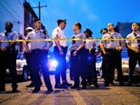 Officers gather for crowd control near a massive police presence set up outside a house as they investigate a shooting in Philadelphia, Wednesday, Aug. 14, 2019. (AP Photo/Matt Rourke)