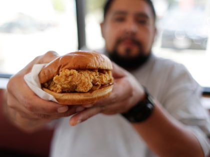 Randy Estrada holds up his chicken sandwiches at a Popeyes, Thursday, Aug. 22, 2019, in Ky