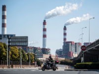 A man rides his scooter near the Shanghai Waigaoqiao Power Generator Company coal power plant in Shanghai on March 6, 2017. / AFP PHOTO / Johannes EISELE (Photo credit should read JOHANNES EISELE/AFP/Getty Images)