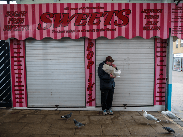 GREAT YARMOUTH, ENGLAND, - FEBRUARY 07: Birds look on as a man eats a bag of chips outside a closed sweet shop in Great Yarmouth Market on February 7, 2017 in Great Yarmouth, United Kingdom. The town of Great Yarmouth on the East Coast of England voted by 72% to …