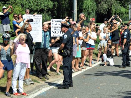 Demonstrators watch as the motorcade of President Trump drives past as he arrives for a campaign fundraiser in Water Mill, New York Friday. (SAUL LOEB/AFP/Getty Images)