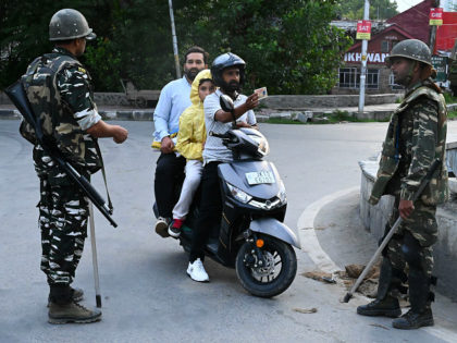 A motorist shows his identity card to a security personnel after being stopped for questioning at a roadblock during a lockdown in Srinagar on August 12, 2019. - Indian troops clamped tight restrictions on mosques across Kashmir for Eid al-Adha festival, fearing anti-government protests over the stripping of the Muslim-majority …