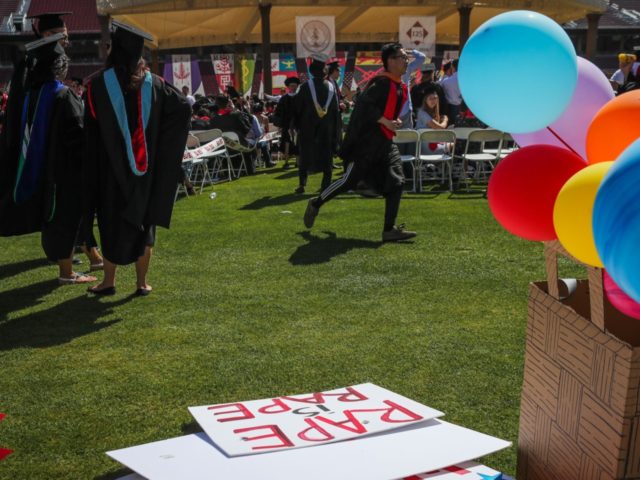 Students walk by a sign that lays on the ground that was made in support of a Stanford rap