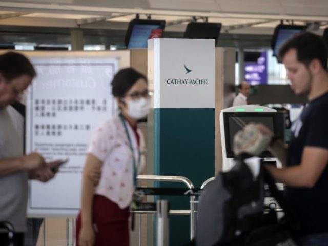 A staff member helps passengers in the Cathay Pacific Airways check-in area at Hong Kong's