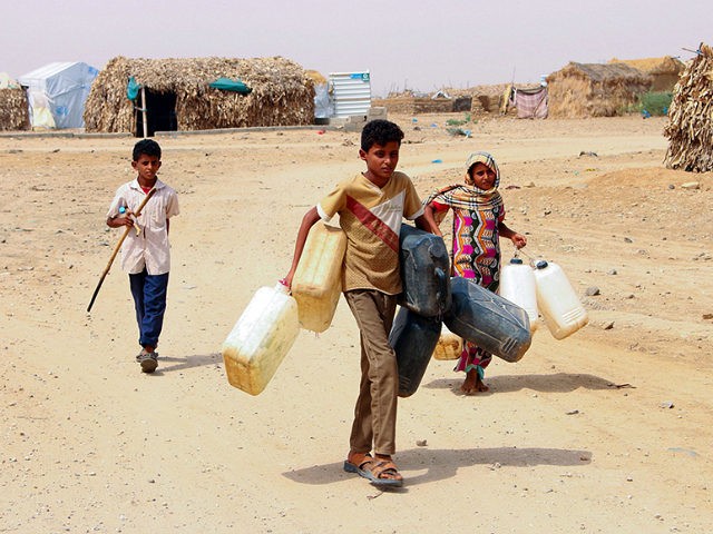Displaced Yemenis from Hodeida fill water containers at a make-shift camp in a village in
