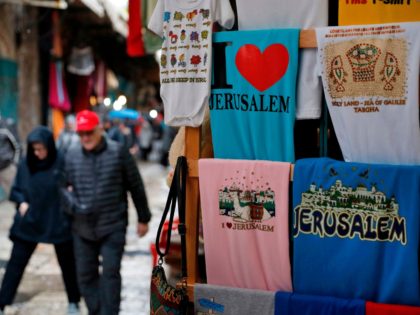 Tourists walk past souvenir T-shirts for sale in Jerusalem's Old City on December 6, 2017.