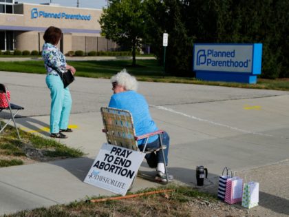 Abortion protesters stand in the driveway of a Planned Parenthood clinic in Indianapolis, Friday, Aug. 16, 2019. Planned Parenthood of Indiana and Kentucky is receiving a nearly $1 million funding boost and is adding staffers under its merger with the group's Seattle-based affiliate. (AP Photo/Michael Conroy)