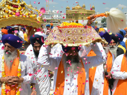 An Indian Sikh priest (R) carries the Sikh holy book during a procession from the Sri Akal