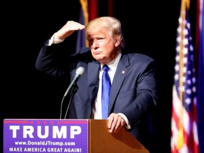 Republican presidential candidate Donald Trump shields his eyes from the lights as he take