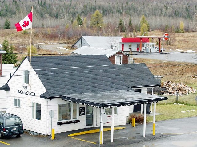Ouellete's Gaz Bar, background, sits in Estcourt Station, Maine, 150 feet from the U.S. border with Canada at the town of Pohenegamook, Quebec, Monday, Nov. 11, 2002. The gas station is only accessible by car from Canada, and is in view of the Canadian Customs office, foreground. Michel Jalbert, of …