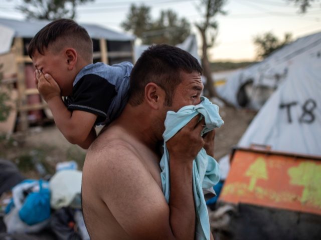 OPSHOT - A man and a boy react cry after police fired tear gas during clashes outside the refugee camp of Moria on the Greek island of Lesbos, on September 29, 2019. - At least two migrants died on September 29 in a fire at a Greek island refugee camp, …