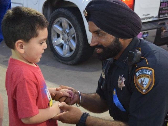 Deputy Sandeep Dhaliwal talks with a young boy at a memorial at the scene of the August 20