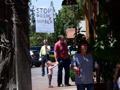 A protestor holds a sign while keeping his distance from the bookstore where drag queens read to adults and children during Drag Queen Story Hour at Cellar Door Books in Riverside, California on June 22, 2019. - Athena and Scalene, their long blonde hair flowing down to their sequined leotards …