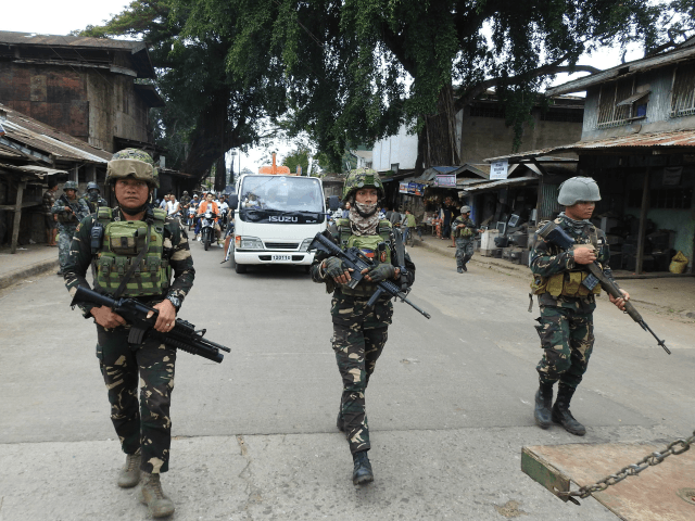 Philippine soldiers escort a hearse during the funeral procession of a victim killed in th