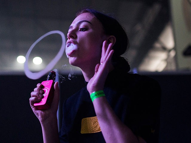 A woman blows smoke from an electronic cigarette as she takes part in a vaping trick compe
