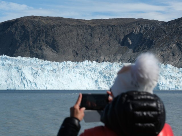 EQIP SERMIA, GREENLAND - JULY 31: A visitor on a tourist boat photographs the 200 meter tall face of the Eqip Sermia glacier, also called the Eqi glacier, during unseasonably warm weather on July 31, 2019 at Eqip Sermia, Greenland. The Eqip Sermia glacier is located approximately 350km north of …