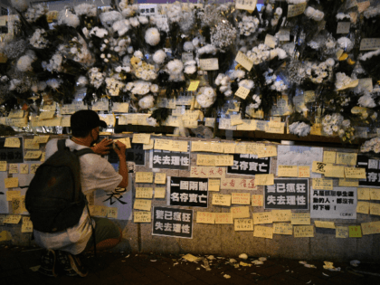 A man writes a note amongst flowers left outside the Prince Edward MTR underground train station in Hong Kong on September 4, 2019, for protesters who were injured during police arrests on August 31. - Hong Kong's leader on September 4, 2019 bowed to a key demand of pro-democracy protesters …