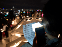 A pro-democracy demonstrator sings an anthem as others form a human chain on Victoria Peak in Hong Kong on September 13, 2019. - Thousands of Hong Kong pro-democracy activists used torches, lanterns and laser pens to light up two of the city's best-known hillsides on September 13 night in an …