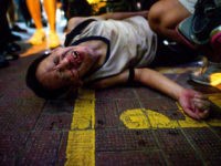 TOPSHOT - An unidentified man reacts after being beaten by a group of people after a protest in Causeway Bay district in Hong Kong on September 15, 2019. - Hong Kong riot police fired tear gas and water cannons at hardcore pro-democracy protesters hurling rocks and petrol bombs on September …