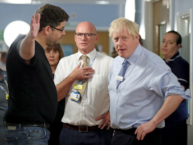 Britain's Prime Minister Boris Johnson (R) listens as the father of a young girl, who is being treated in the Acorn childrens' ward, expresses his anger over hospital waiting times during his visit to Whipps Cross University Hospital in Leytonstone, east London on September 18, 2019. (Photo by Yui Mok …